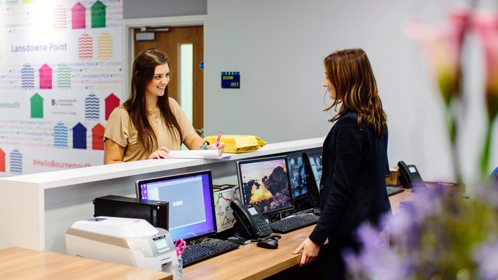 Student talking with Kaplan Living employee at the front desk