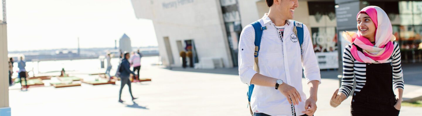 Two students laughing whilst taking a walk in the city