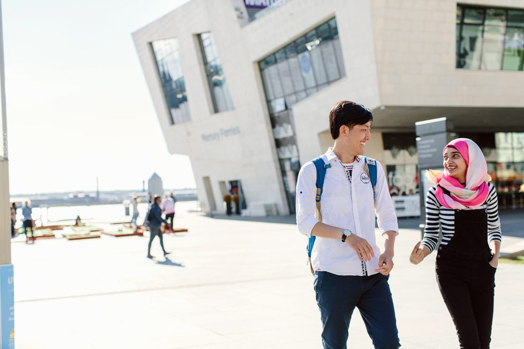 Two students laughing whilst taking a walk in the city