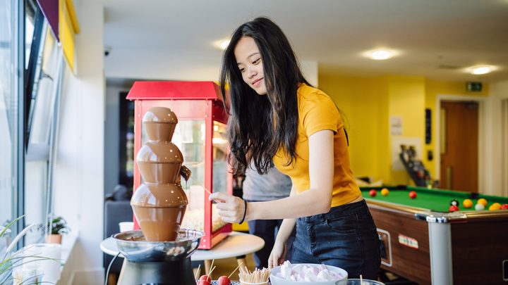 A student interacting with a chocolate fountain in the common space