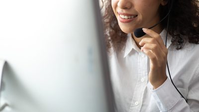 Woman in a Call with headset facing a Monitor