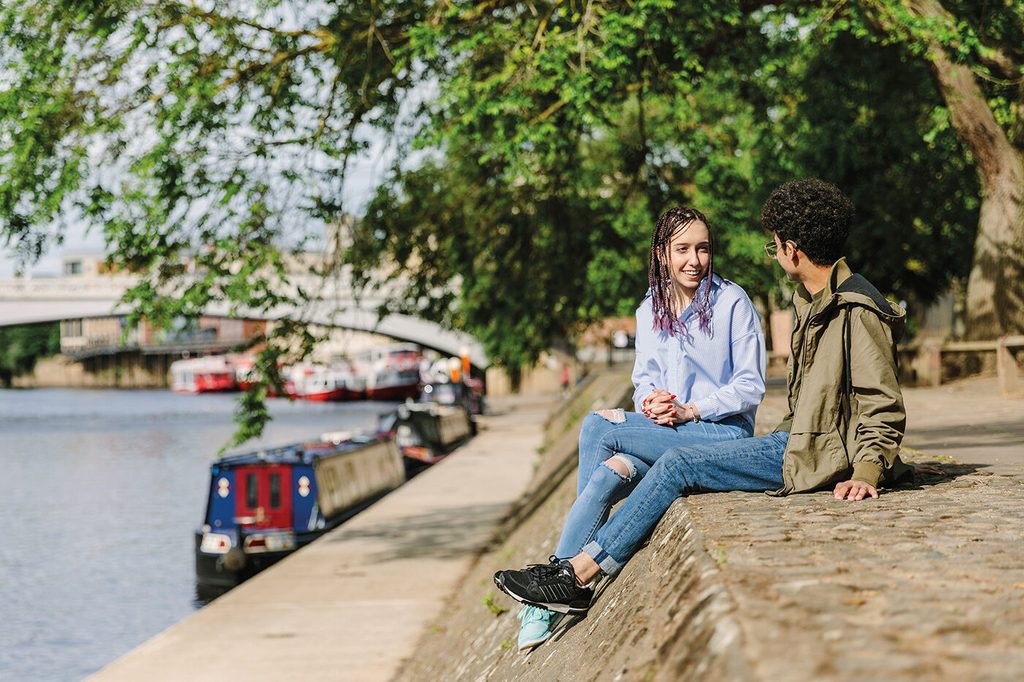 Two students chatting by the water in York