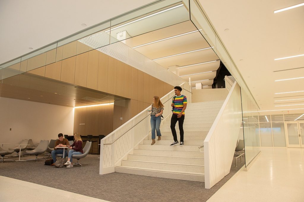 Two students walking down the stairs in a Pace building