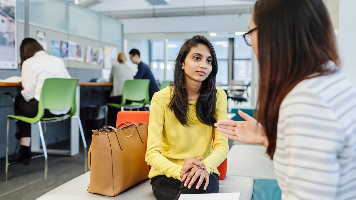 Two students chatting inside a Pace university building