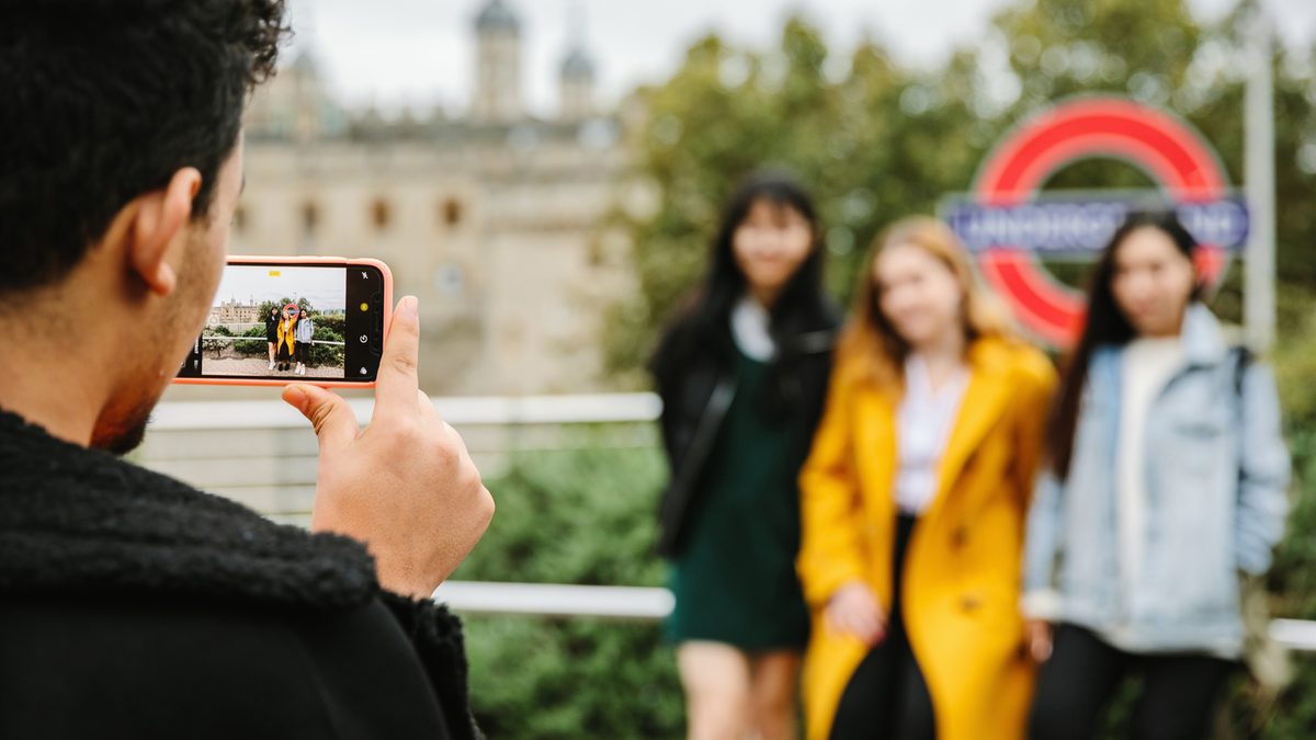Student having their photo taken outside the Tower of London Underground station