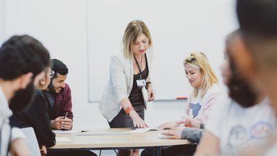 Students in classroom with teacher explaining assigment