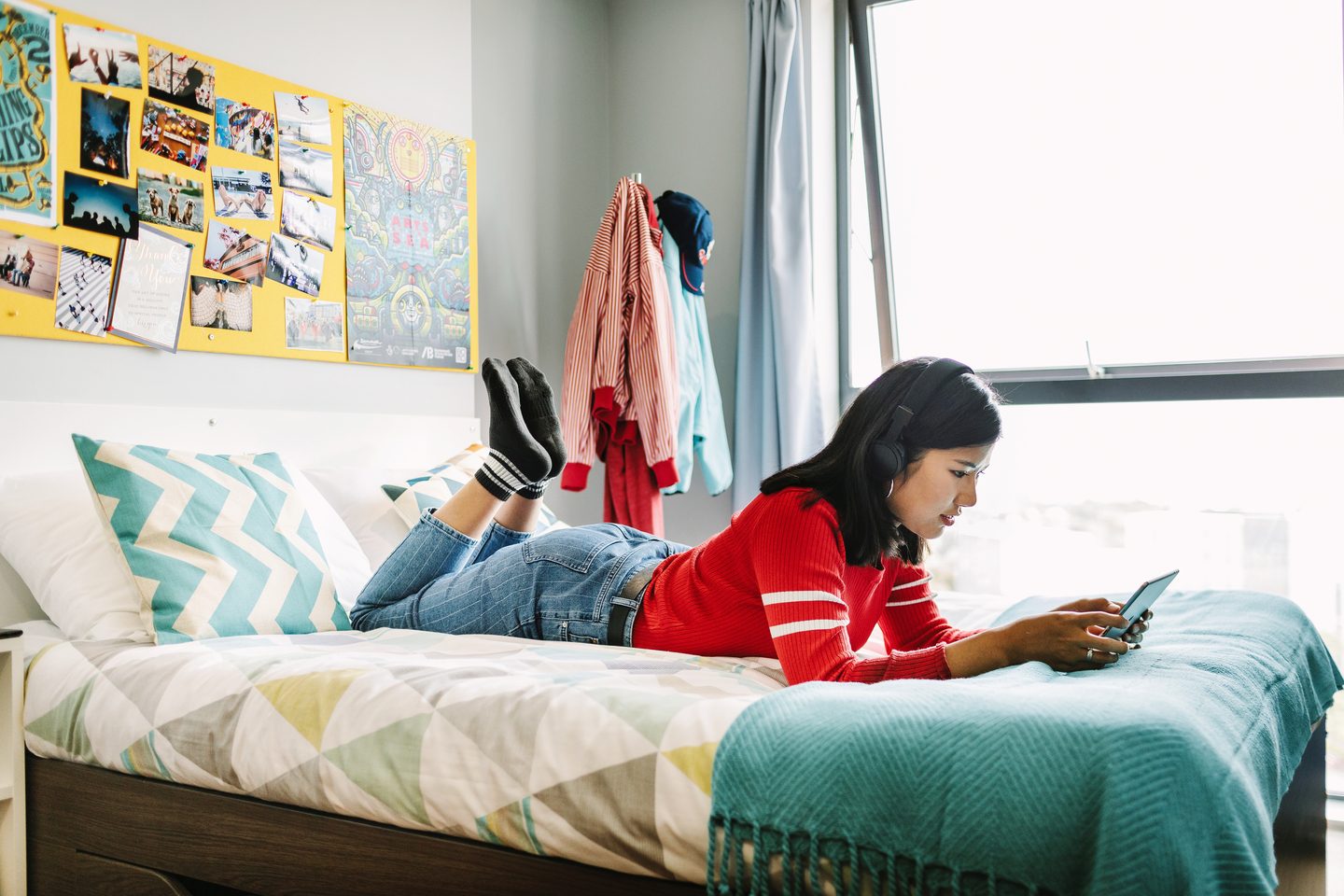 Student laid on the bed using a tablet in the student accommodation