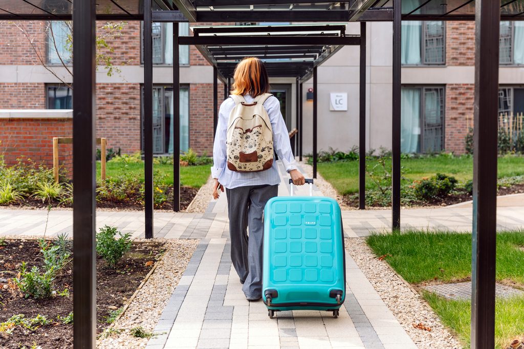 A student entering the building with her luggage