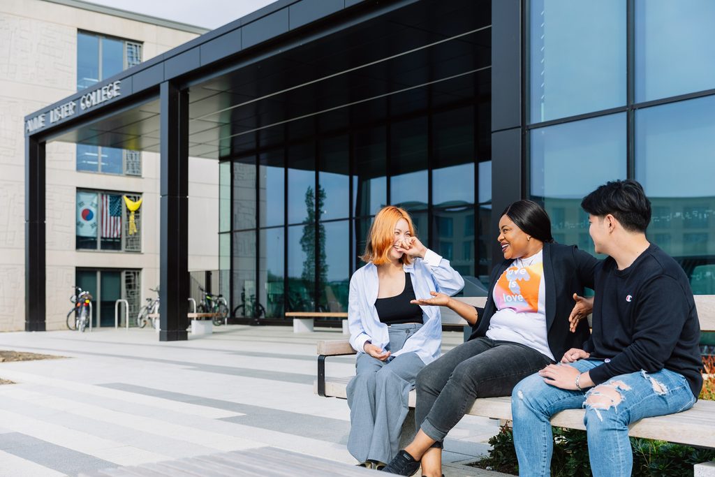 Students sitting on the bench in front of Anne Lister Building and having a good time