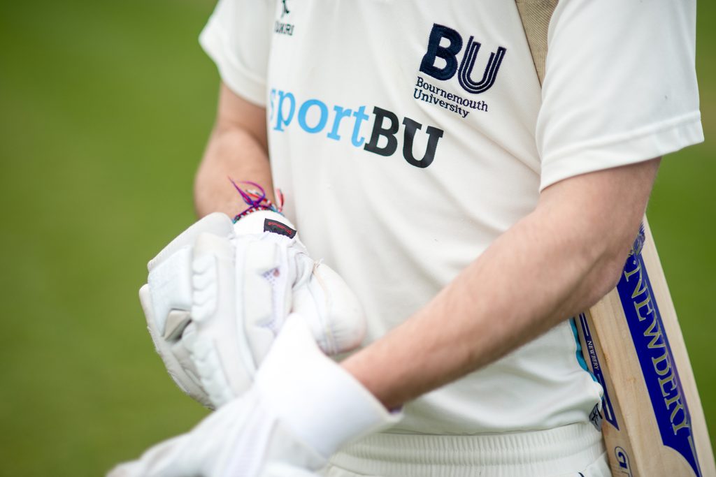 A cricket player wearing a batting glove while holding a cricket bat