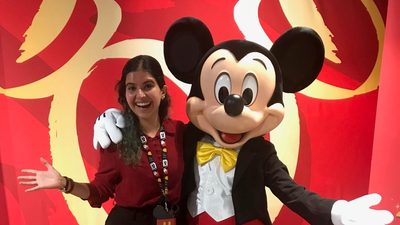 Student posing with Mickey Mouse character from Disney