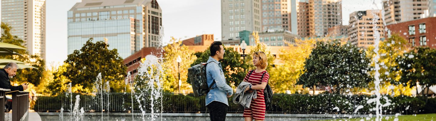 two students talking next to the fountains of the city of Boston