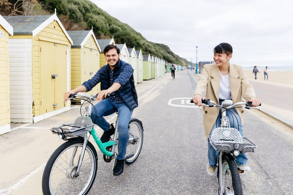 Two students cycling along the beach in Bournemouth