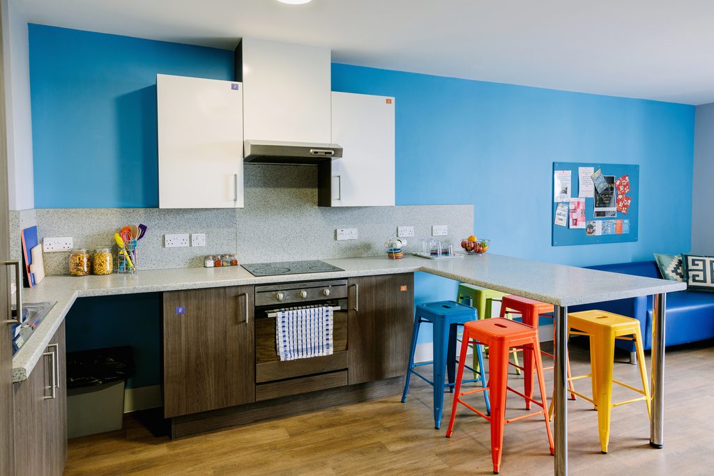 Shared kitchen with hob, oven, cupboards, stools and a dining table