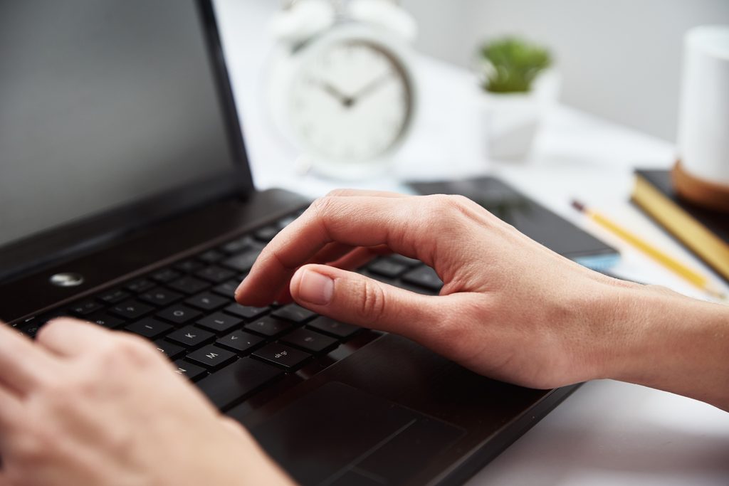 A woman typing on a laptop keyboard