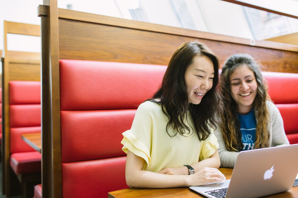Students smiling and looking at laptop