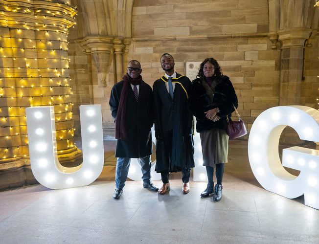 Student in a graduation ceremony with his parents