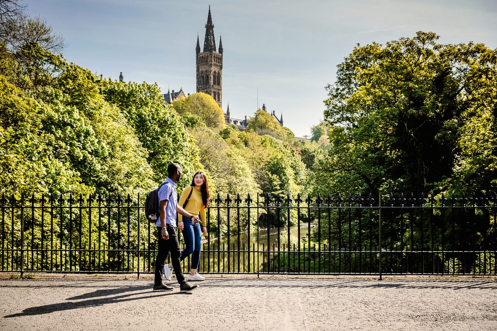 Students walking on the Kelvin Bridge with view of Glasgow University Gilbert Scott Building