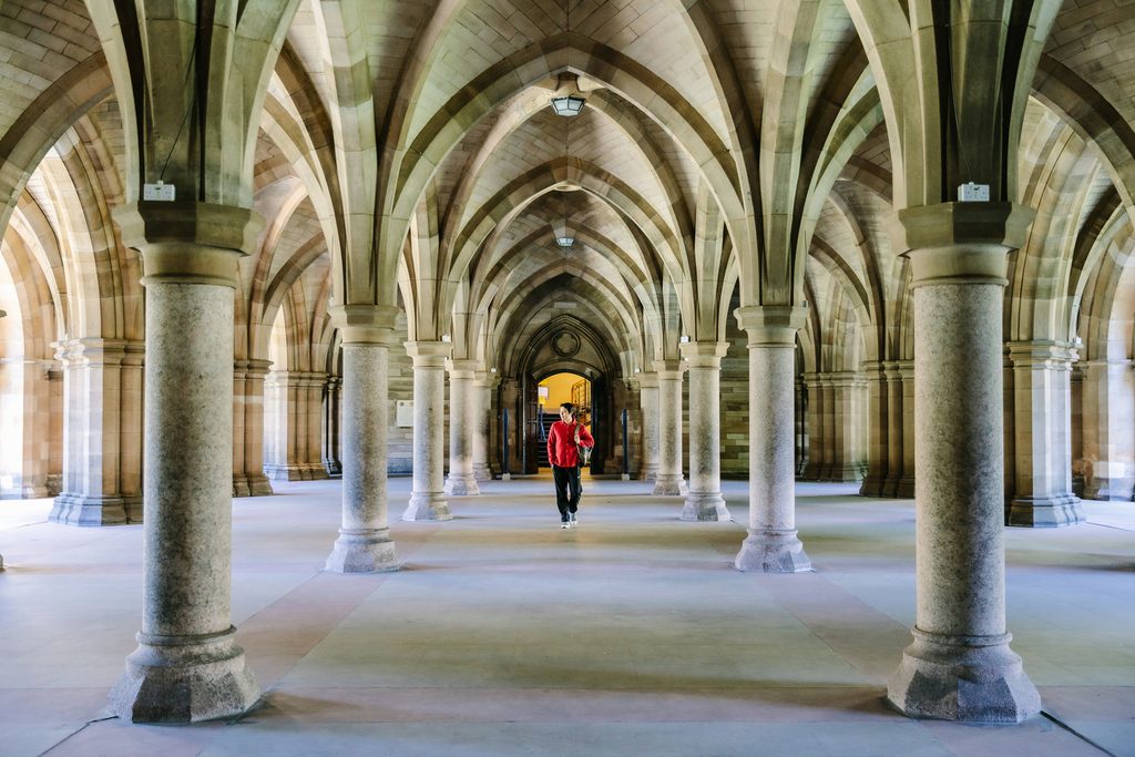 A student walking inside the Gilbert Scott Building