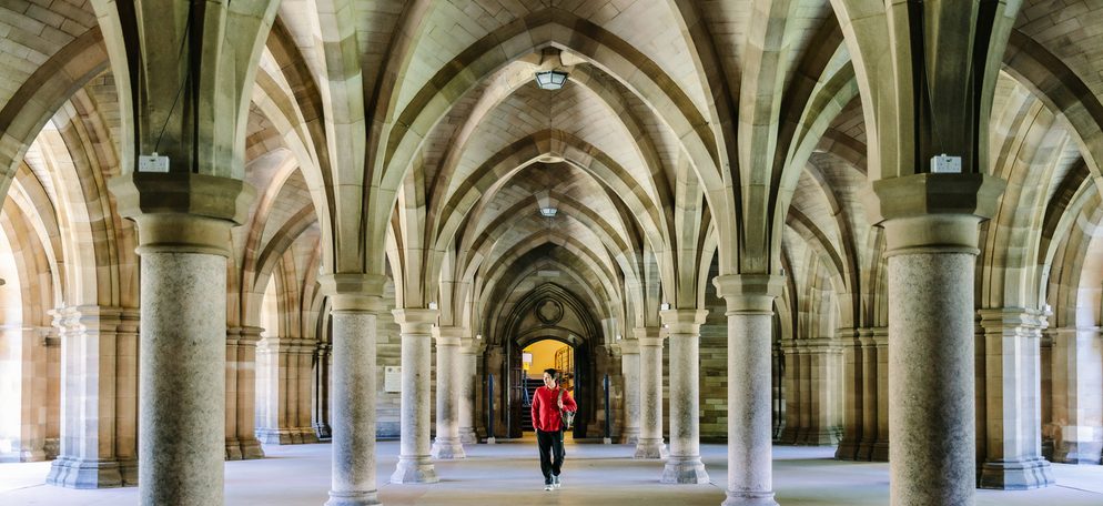 A student walking inside the Gilbert Scott Building