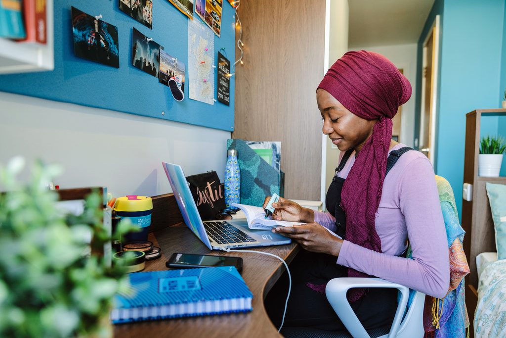 Student studying on her book with her laptop open