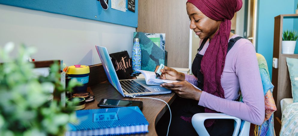 Student studying on her book with her laptop open