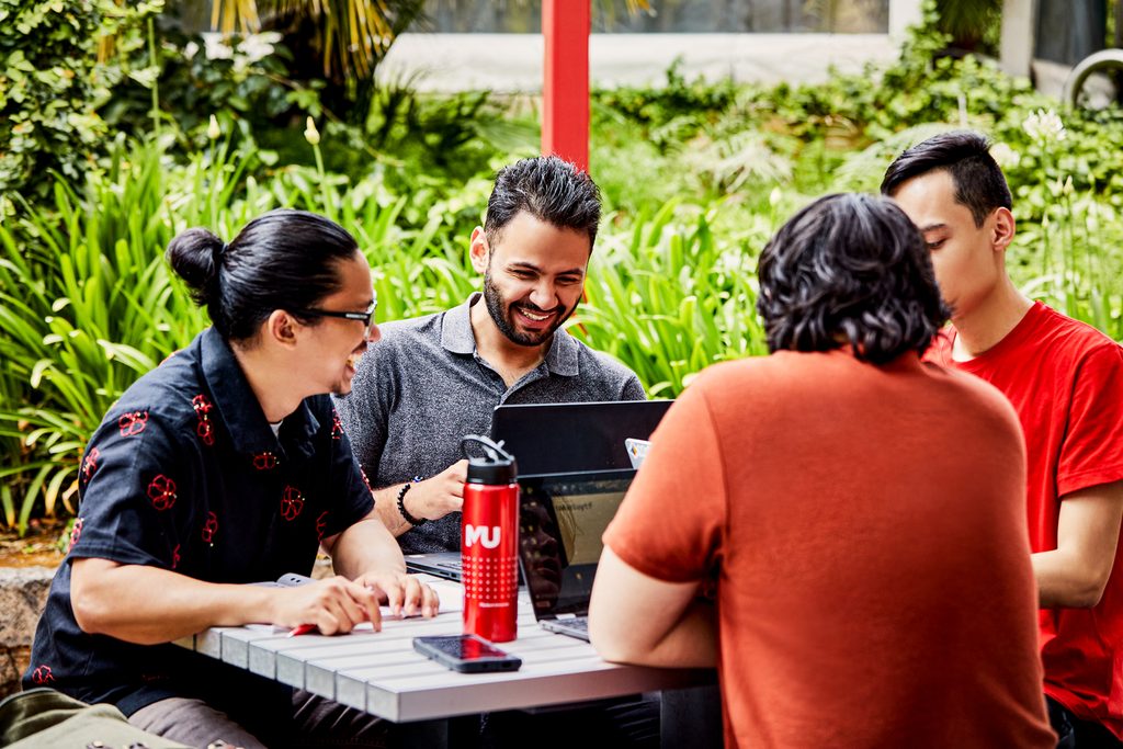 Murdoch University students sat on a picnic table having fun
