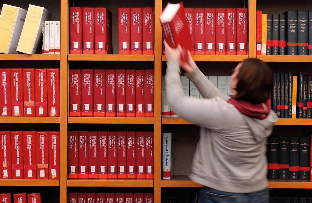a student putting a book on the shelf