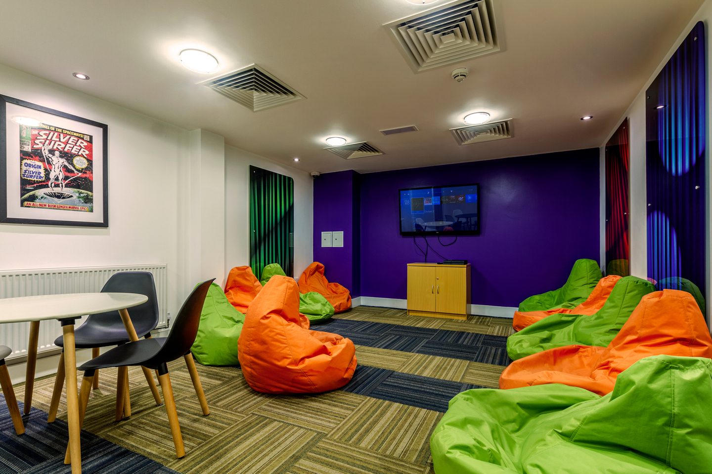 Shared area with a television, a table, chairs and beanbags