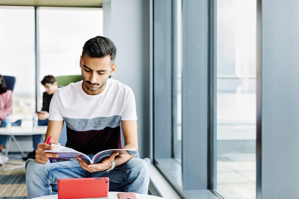 Student reading a book in a social space