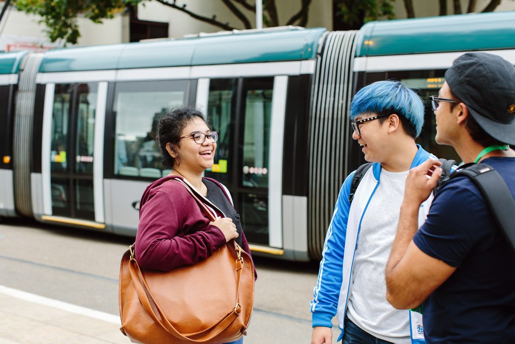 students chatting on the street while a tram is passing by