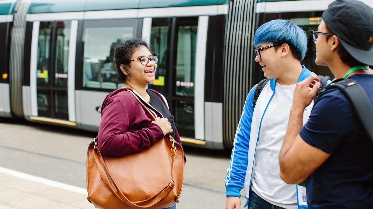 students chatting on the street while a tram is passing by