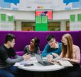 A group of students talking, looking a laptop and studying together