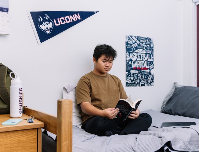 A student reading on his bed in his dorm room