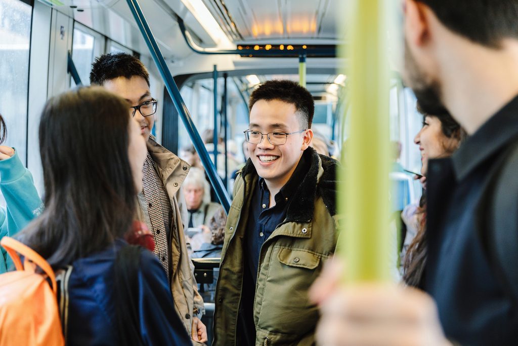 Students standing in the tram and smiling to each other
