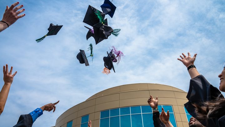 UCONN students toss their graduation caps in the air in celebration of commencement