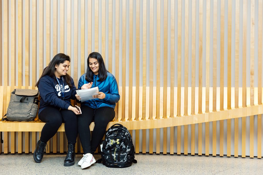 Two UCONN students laughing on a bench