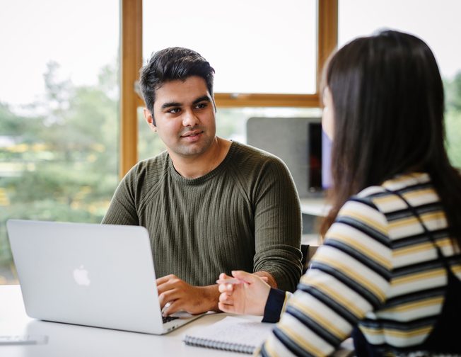 A UNIC student chatting to another student whilst on his laptop