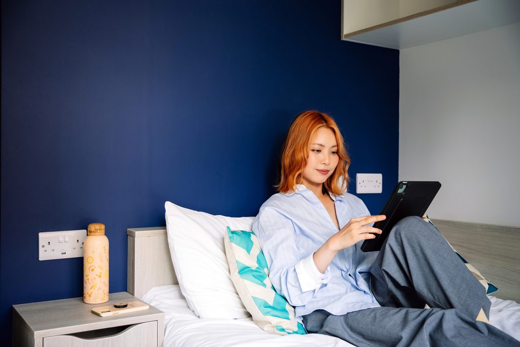Student lying on the bed an looking at tablet