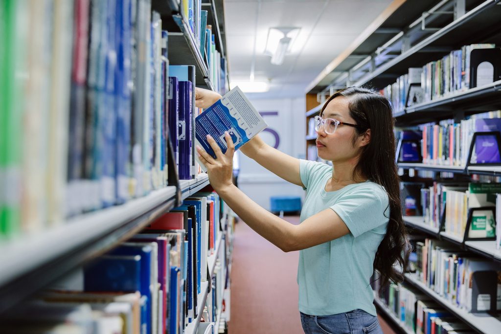 A UWE Bristol International College putting back the book in the shelf