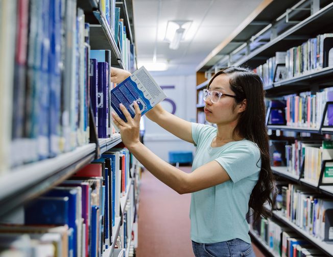 A UWE Bristol International College putting back the book in the shelf
