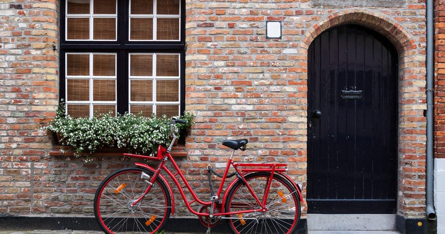 Red bicycle leaning on a brick wall