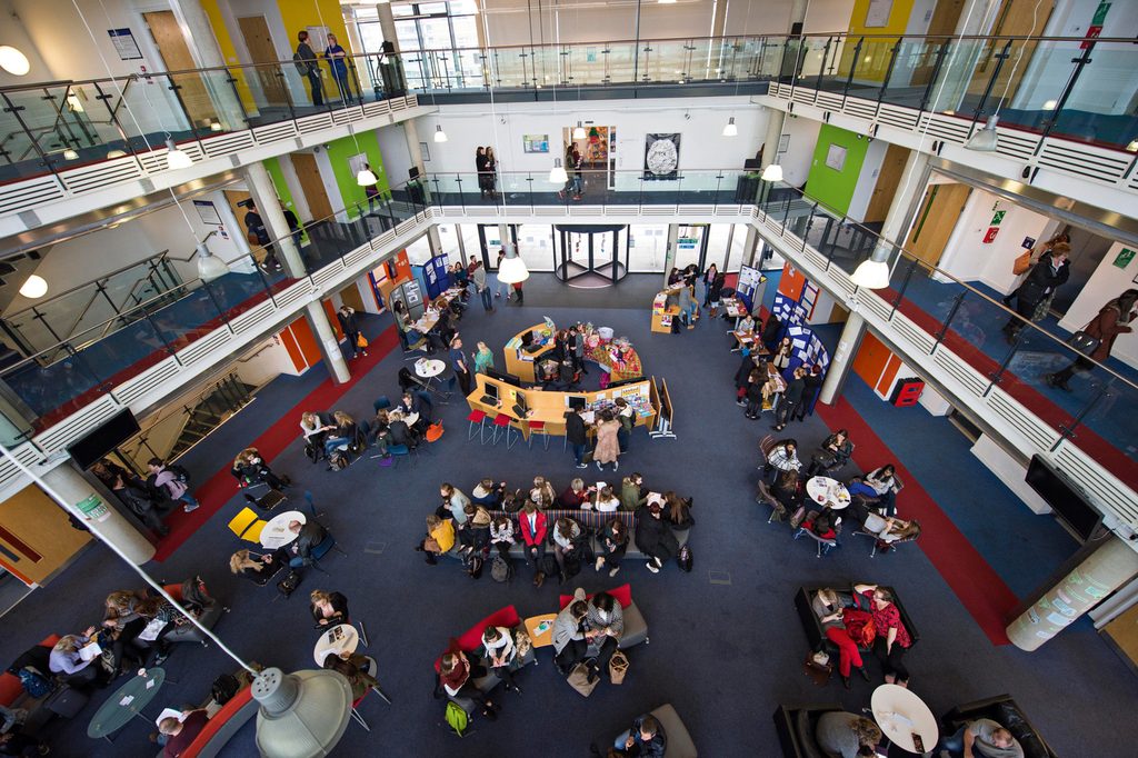 Students in groups are talking to each other and studying inside the building