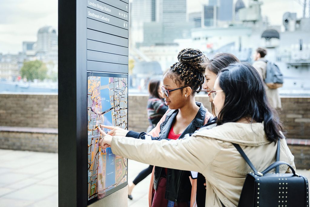 Three students looking at city map on the board
