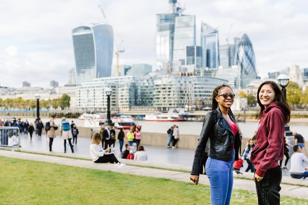 2 students standing next to the river side and smiling to the camera