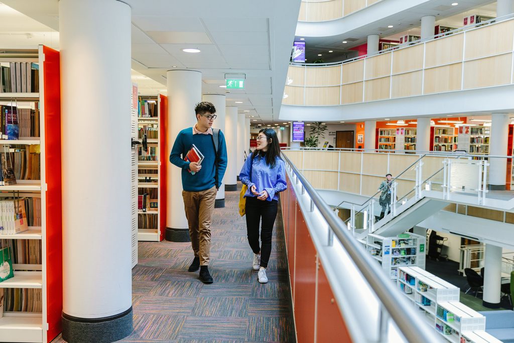 Two NTIC students walking in the library