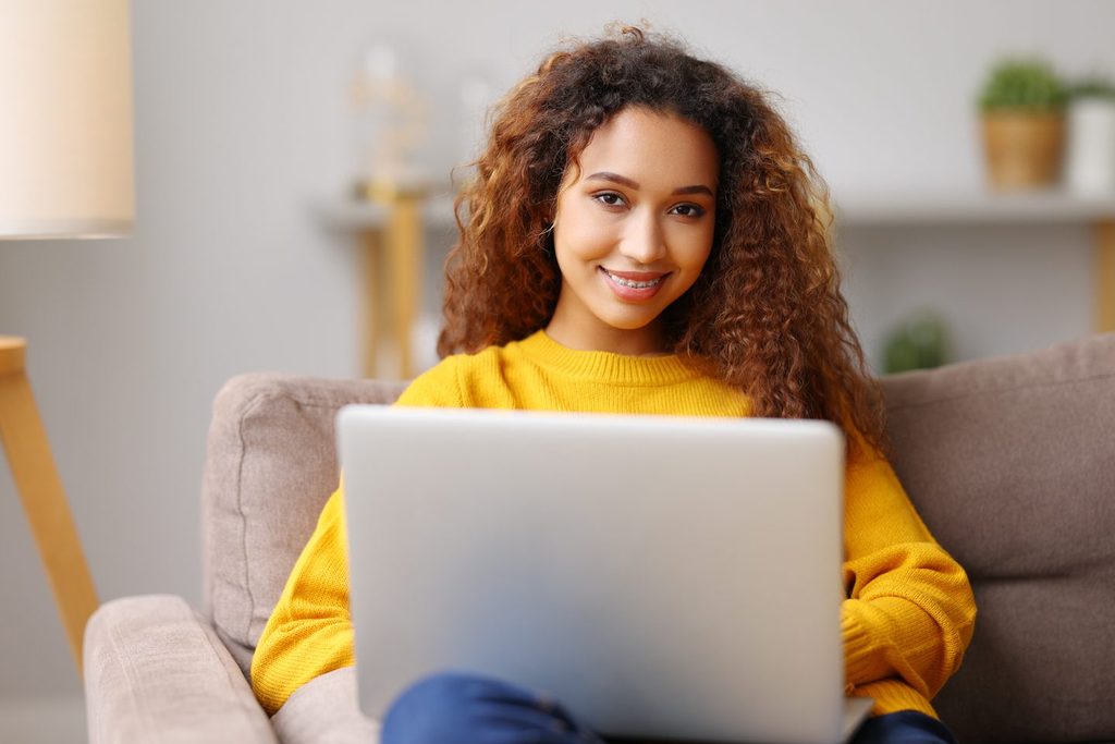 A girl smiling with her laptop on her lap