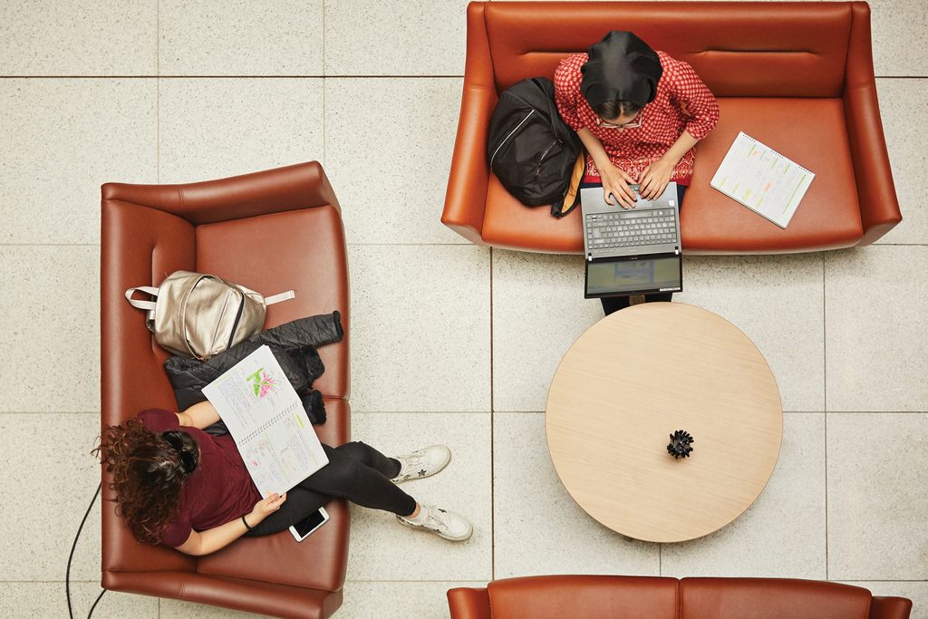 Student working on laptops and pads on sofas