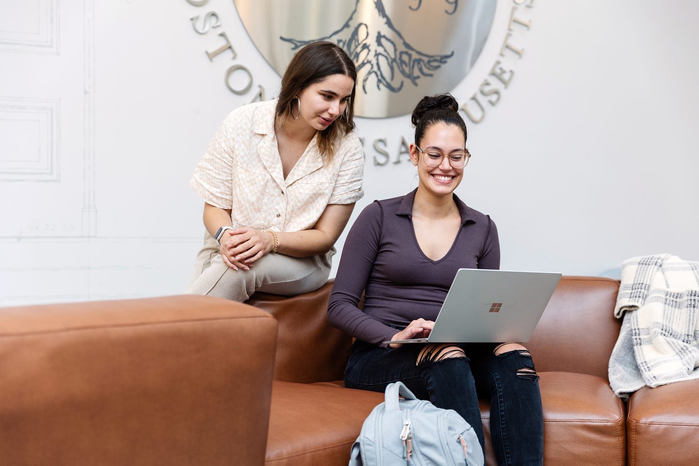 Students sitting on a coach and looking at a laptop