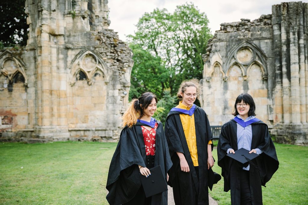 Three students out and about wearing graduation robes